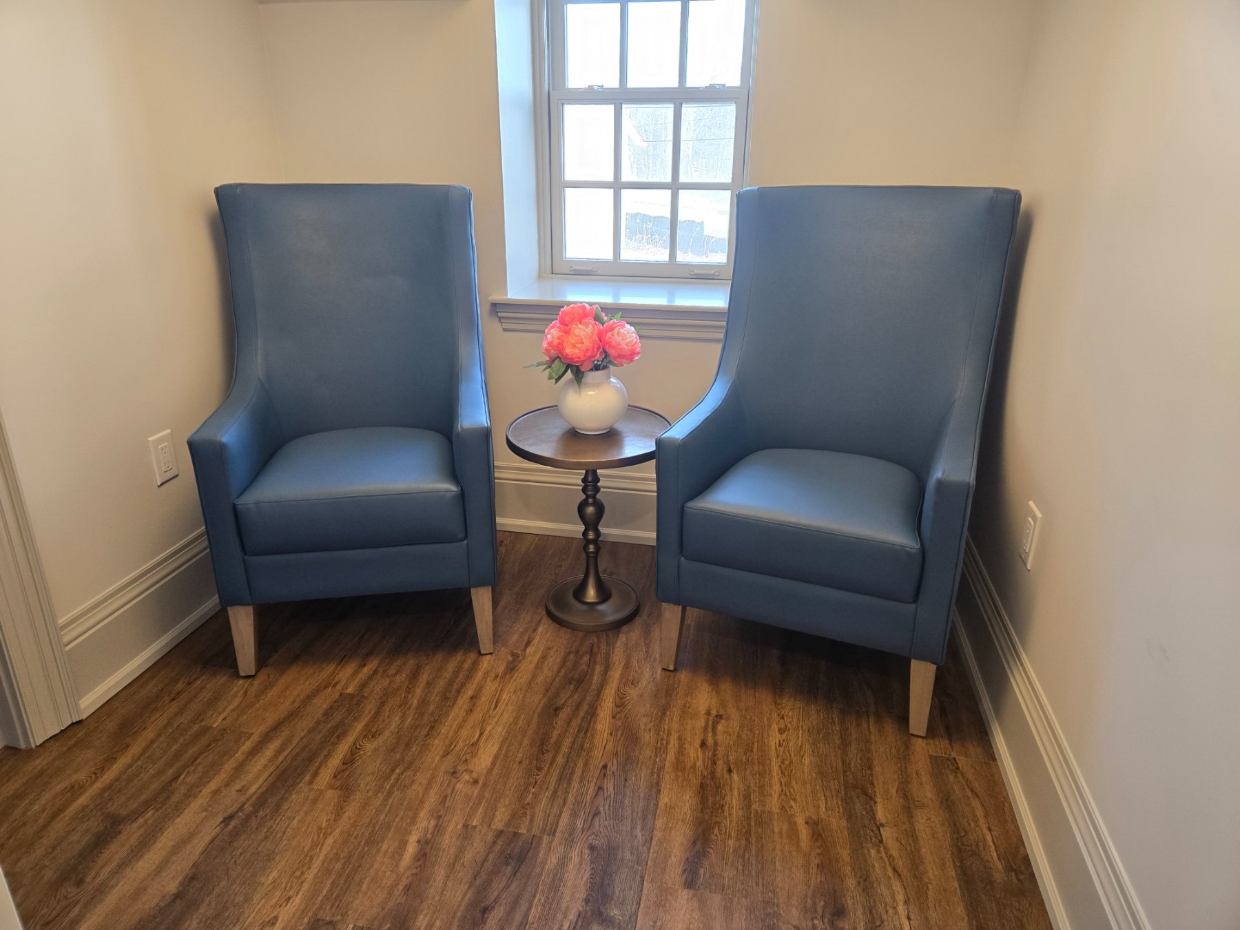 Resident sitting nook at CIBPA Place with paired high-back blue leather lounge chairs and a round accent table