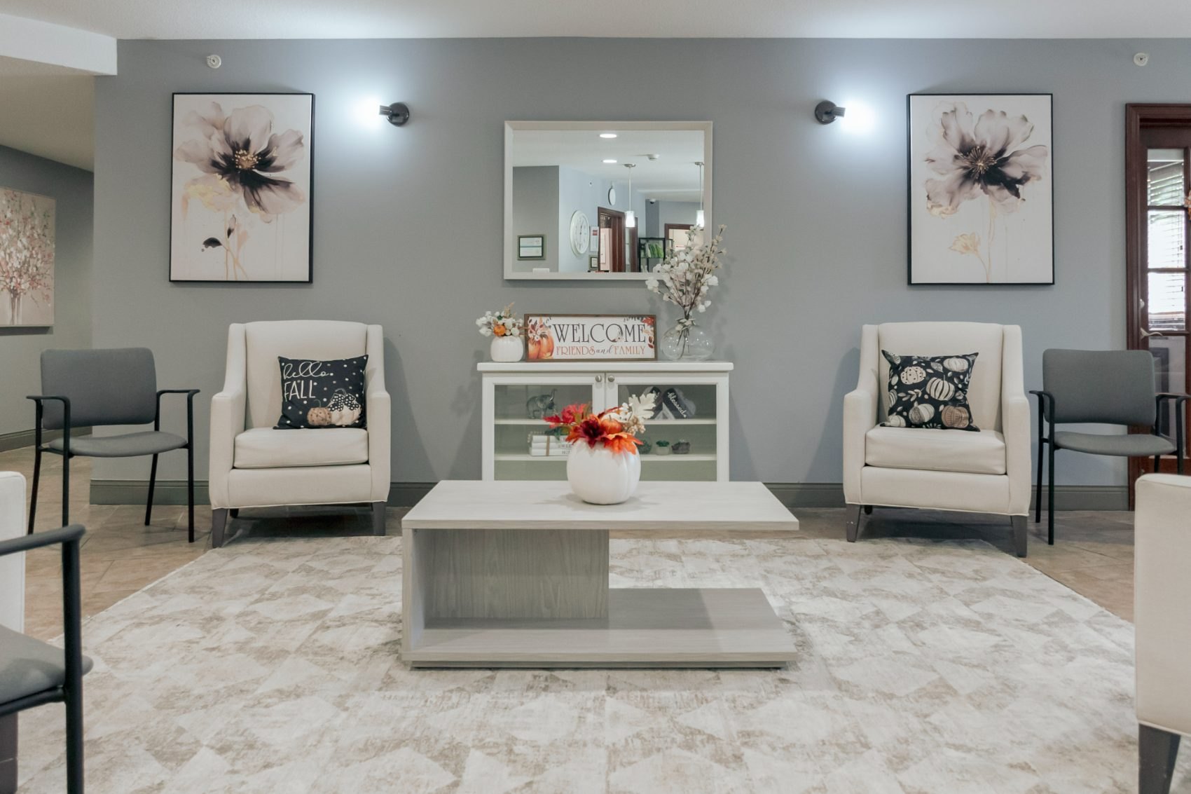Stone Lodge lobby furnished with cream wing chairs, a whitewashed coffee table, and floral artwork